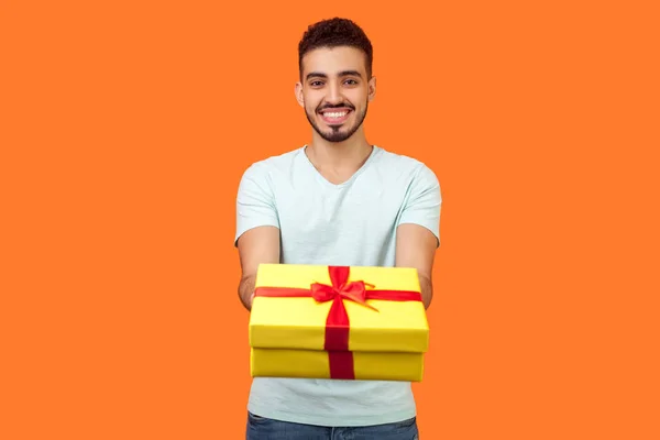 Portret szczęśliwej hojnej brunetki mężczyzna daje pudełko prezentów do kamery — Zdjęcie stockowe