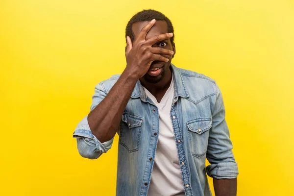 Retrato de homem interessado positivo espreitando através dos dedos com — Fotografia de Stock