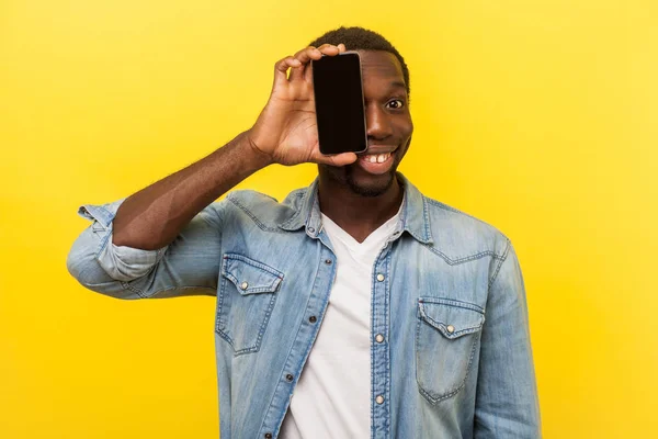 Porträt eines fröhlichen Mannes, der sein halbes Gesicht mit dem Handy bedeckt — Stockfoto