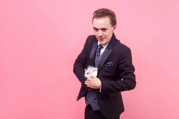 Retrato de homem positivo engraçado escondendo coelho branco em seu smoking — Fotografia de Stock