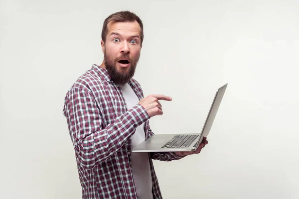 Portrait of shocked computer user, bearded man pointing at lapto — Stock Photo, Image