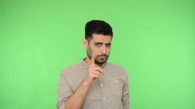 Bunu yapma, dikkatli ol! Gömleği tüylü, kumral, uyarı parmağı hareketi yapan ve onaylamayan, hoşnutsuz suratıyla hayır diyen bir adam. Stüdyo içi çekim, yeşil arka plan, krom anahtar.