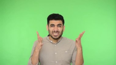 Tişörtlü sinirli, çılgın esmer adam dişlerini sıktı ve elleri nefretle kaldırıldı. Öfkeyle hırıldıyor, kavga ediyor, çatışma konseptiyle. Stüdyo içi çekim, yeşil arka plan, krom anahtar.
