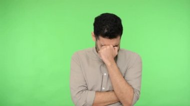 Üzüntülü genç bir adam. Ellerinde yüzünü saklayıp ağlıyor, depresyona giriyor, orta yaş bunalımına giriyor. Çaresiz ve umutsuz hissediyor. Stüdyo içi çekim, yeşil arka plan, krom anahtar.