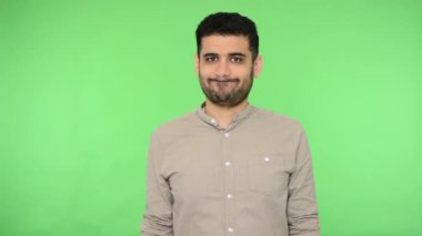 Hoşlanmamak, kötü geri bildirim. Tişörtünde kılları olan hoşnutsuz esmer bir adam baş parmak işareti yapıyor, hayır diyor, tatminsiz bir suratla inkar ediyor. Stüdyo içi çekim, yeşil arka plan, krom anahtar.