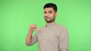 Ben buyum! Tişörtünde tüyleri olan, mutlu bir şekilde gülümseyen, kendini beğenmiş, kibirli ve bencil bir adam. Stüdyo içi çekim, yeşil arka plan, krom anahtar.