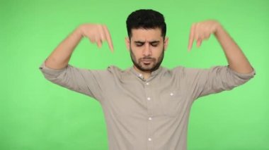 Üstü başı kıllı, otoriter esmer bir adam sinirli ve otoriter bir ifadeyle buraya işaret ediyor ve emir veriyor, hemen şimdi. Stüdyo içi çekim, yeşil arka plan, krom anahtar.
