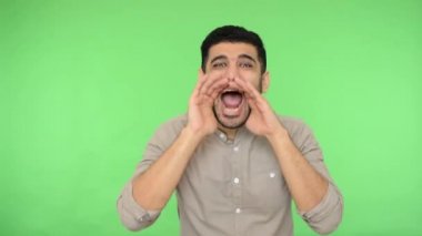 Dikkat! Gömleği tüylü kızgın esmer adam ellerini açık tutuyor ve her yandan bağırıyor, yüksek sesle anons ediyor. Stüdyo içi çekim, yeşil arka plan, krom anahtar.