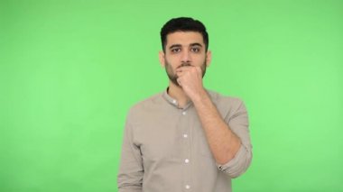 Tişörtünde kıvırcık tüylü esmer adam fermuar dudak hareketi gösteriyor. Yani kimseye söylemeyeceğim. Sonsuza kadar sır olarak kalacak, gizli bilgi. Stüdyo içi çekim, yeşil arka plan, krom anahtar.