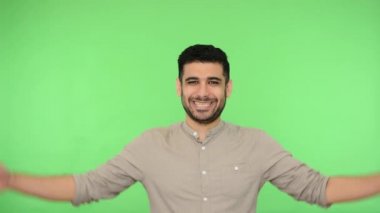 Heyecanlı, neşeli, tişörtlü, tüylü, ev tabelası yaptıran, başını sokacak bir çatı jesti yapan, mutlu, güvende hisseden, sigorta anlayışı, ev alışverişi yapan bir adam. Stüdyo çekimi, yeşil arkaplan