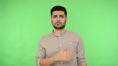 İtaatkar esmer, gömleği göğsünde kıllarla el ele tutuşmuş el ele tutuşmuş ve söz vermek için el kaldırmış. Yemin ederim, sadık ve dürüst görünüyorum diyor. Stüdyo içi çekim, yeşil arka plan, krom anahtar.