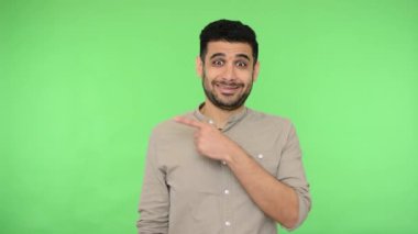 Bana bak! Tişörtlü neşeli esmer adam fotokopi alanını işaret ediyor ve onaylı bir şekilde reklam metni ya da ürün için reklam alanı gösteriyor. Stüdyo içi çekim, yeşil arka plan, krom anahtar.