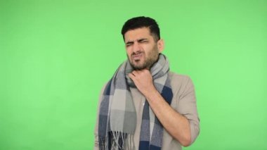 Gömlekli sağlıksız bir genç adam ve grip, boğazı ağrıyan yüksek ateş, öksürük, grip belirtileri. Stüdyo içi çekim, yeşil arka plan, krom anahtar.