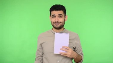 Yapılacak listeyi yaz. Esmer saçlı, kazaklı, elinde kalem ve kağıt defteriyle olumlu bir adam. Onaylı bir şekilde başını sallıyor ve boş bir sayfaya işaret ediyor. Stüdyo çekimi, yeşil arkaplan, krom anahtar