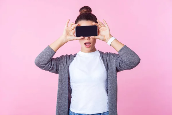 Retrato de adolescente sorprendida cubriendo los ojos con el teléfono celular —  Fotos de Stock