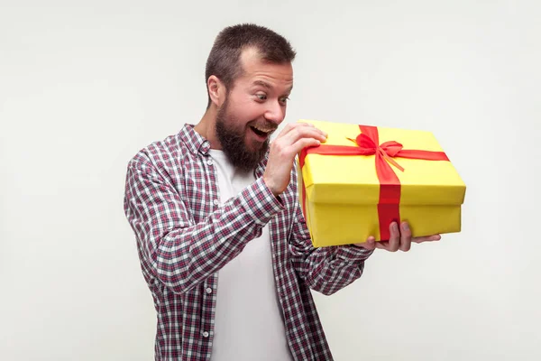 Portret van een opgewonden verraste man met een baard die een groot cadeau uitpakt, — Stockfoto