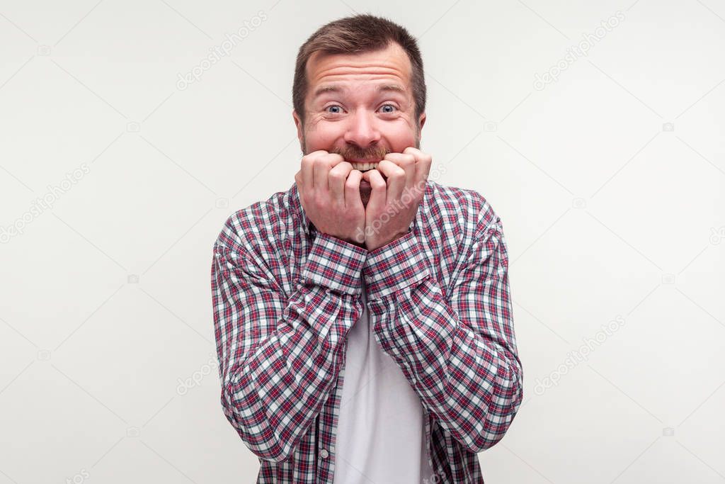 Portrait of worried bearded man looking scared nervous biting hi