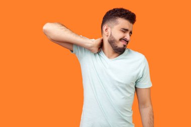 Yorgun esmer adamın portresi boynunu ovuyor ve Grimacin