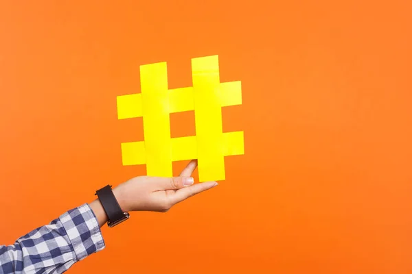 Fechar-se da mão feminina segurando grande grande sinal de hashtag amarelo. em — Fotografia de Stock