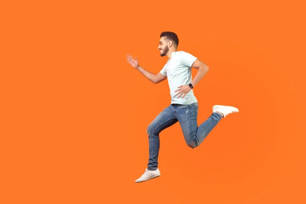 Seitenansicht eines fröhlichen brünetten Mannes, der in der Luft rennt. Indoor Ateliers — Stockfoto