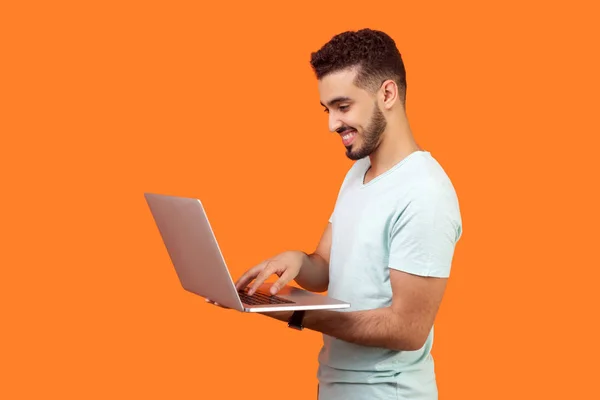 Vue de côté portrait de l'homme brune joyeux travaillant sur ordinateur portable, t — Photo