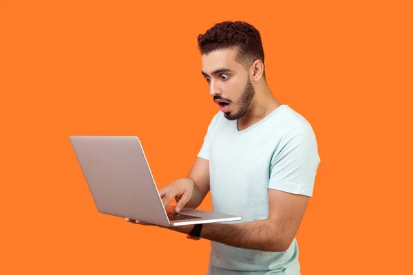 Portret van een jonge man met een baard geschokt door een bericht op de laptop. indo — Stockfoto