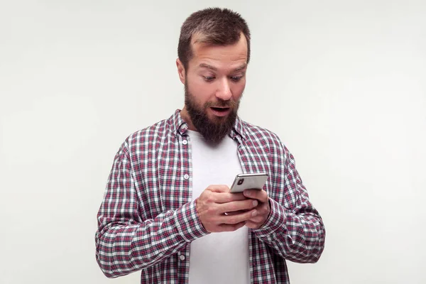 Retrato de homem barbudo surpreso usando smartphone olhando espanto — Fotografia de Stock