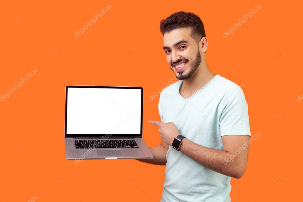 Portrait of positive joyful brunette man holding laptop with bla