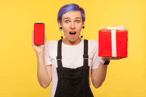 Portrait of surprised shocked hipster girl holding gift box and — Stock Photo, Image