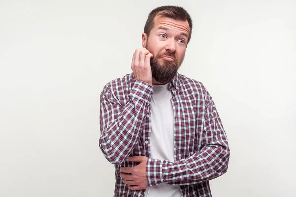 Portrait of thoughtful man in plaid shirt scratching his beard a — Stock Photo, Image