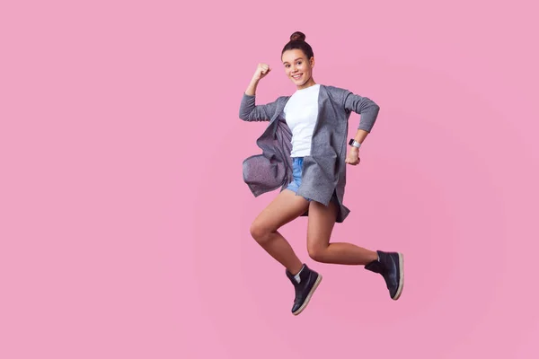 Ekstatisk brunette tenåringsjente som hopper opp i lufta med entusiaer – stockfoto