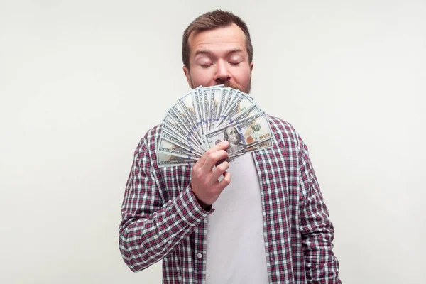 Portrait of greedy bearded man smelling money dollars with pleas — 스톡 사진