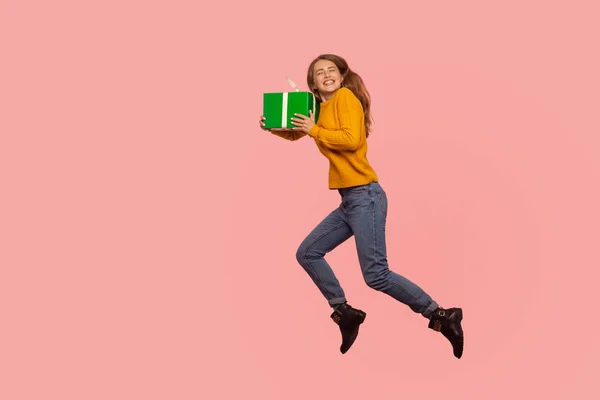 Portrait of extremely happy ginger girl jumping in air with gift — Stock Photo, Image