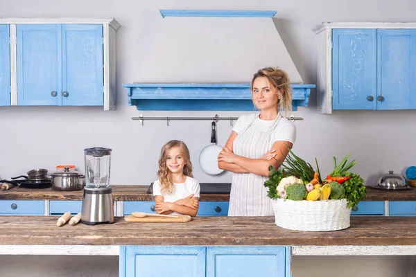 Happy beautiful mother in apron and little daughter standing wit — Stock Photo, Image