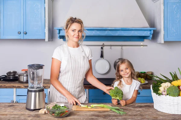 Cheerful pretty mother in apron and little daughter holding broc — Stock Photo, Image