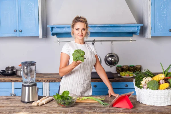 Glad attraktiv kvinna i förkläde håller broccoli och ler mot — Stockfoto