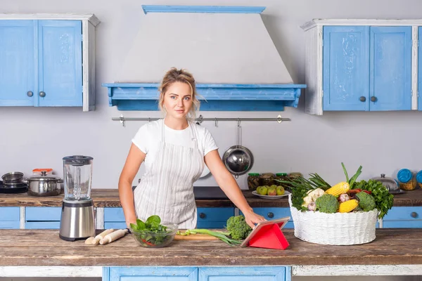 Vacker kvinna i förkläde söker mat recept på internet med — Stockfoto