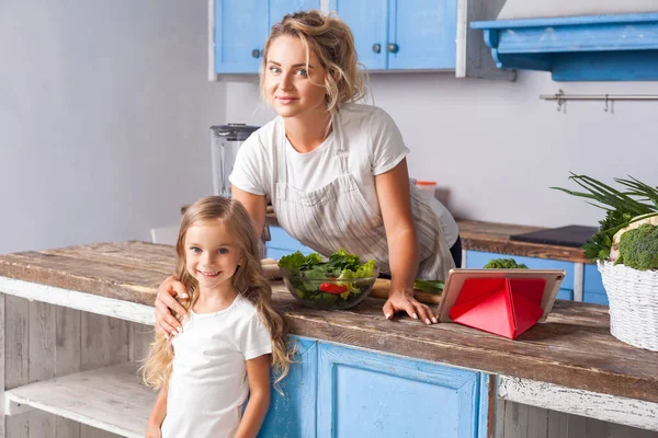 Positive blond woman and her daughter posing on camera in modern — Stock Photo, Image