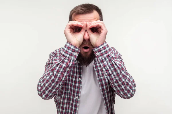 Portret van een nieuwsgierige man met een baard die door zijn vingers kijkt — Stockfoto