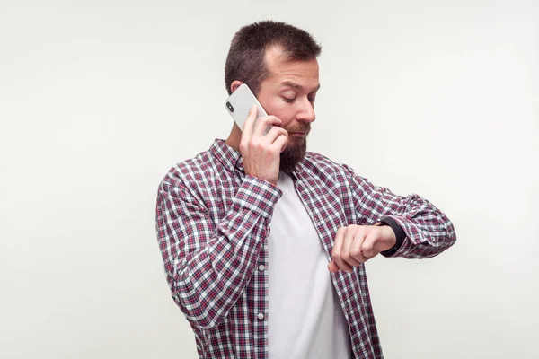 Портрет пунктуального бородатого мужчины, говорящего по телефону и проверяющего футболки — стоковое фото