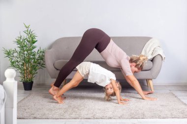 Genç, zinde bir anne ve güzel bir kız birlikte yoga yapıyor. 