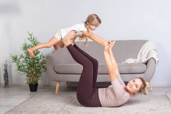 Veselá mladá matka cvičí jógu s malou dcerou, rais — Stock fotografie