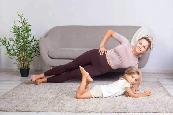 Adorable niño acostado cerca de joven atractiva madre practicando yog — Foto de Stock