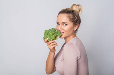 Tüylü, yeşil broc ısıran pozitif bir genç kadının portresi.