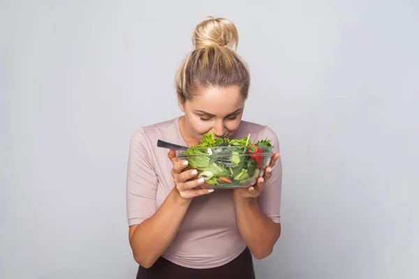 Porträt einer jungen Frau mit Haarbüschel, die an grünem Gemüse schnuppert — Stockfoto