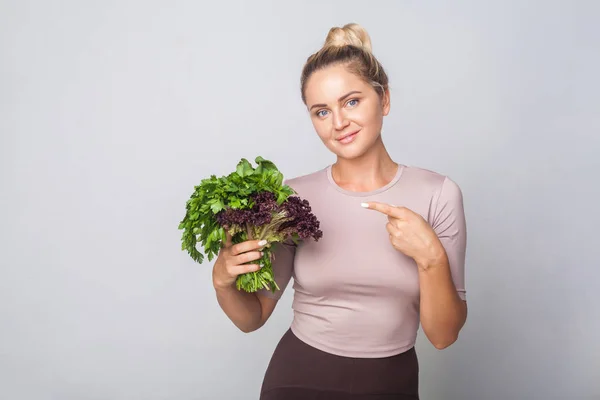 Jovem menina feliz apontando para ervas culinárias frescas, folha verde ve — Fotografia de Stock