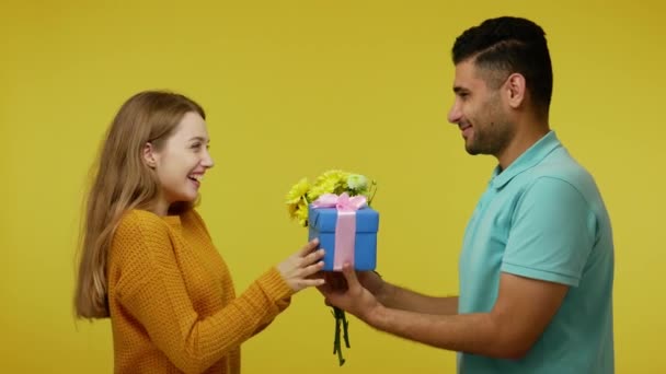 Όμορφος Μελαχρινός Άντρας Δίνει Δώρα Και Λουλούδια Στην Όμορφη Κοκκινομάλλα — Αρχείο Βίντεο