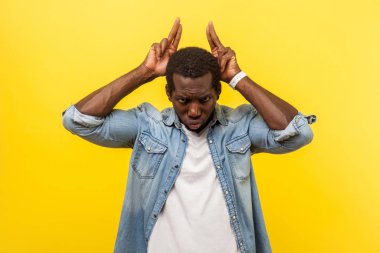 Kot gömlekli, kolları kıvrılmış, elleri başının üstünde boğa boynuzu hareketi yapan saldırgan bir adamın portresi tehlike ve tehdidi ifade ediyor. Sarı arka planda izole edilmiş kapalı stüdyo çekimi