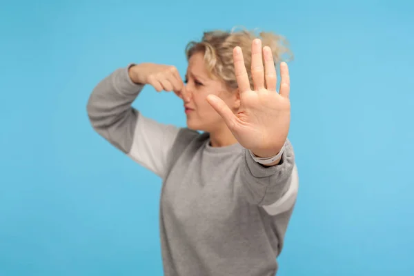 Bad breath. Woman in grey sweatshirt pinching nose with fingers, — 스톡 사진