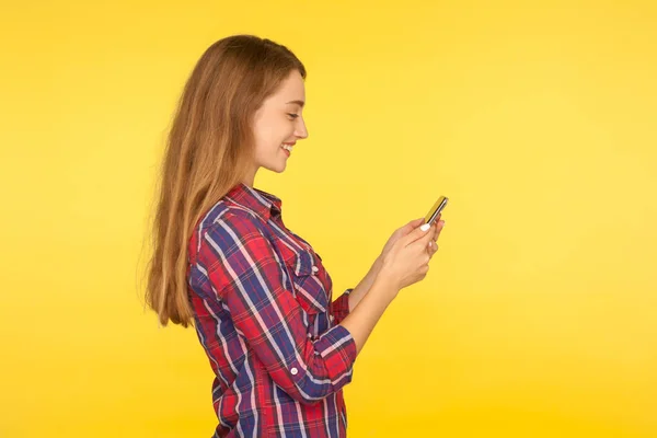 Side view of mobile customer smiling, happy girl in shirt typing — 스톡 사진